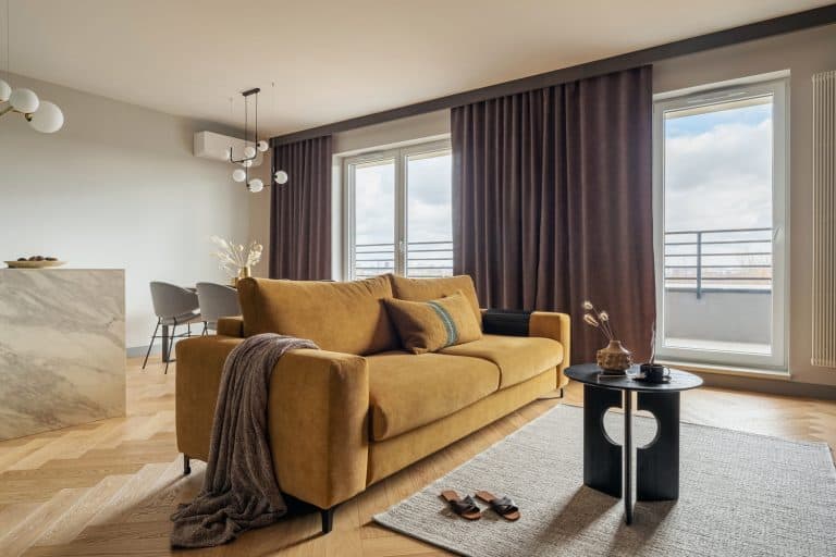 Creative and modern open space interior design with yellow sofa, grey carpet and coffe table . Grey carpet on the herringbone parquet with coffe table, brown curtain in windows. Template. - How High To Hang Curtains For An 18-Foot Ceiling